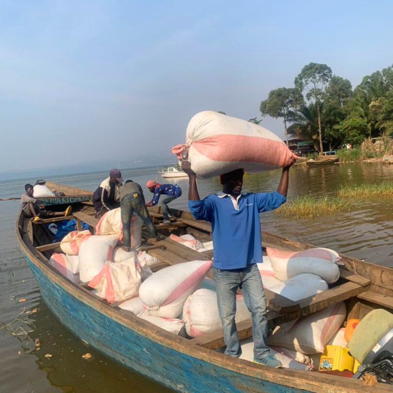 image of man ready to get of a cargo boat ferrying coffee parchment for Rutasoka Coffee, carrying a heavy sack of the coffee parchment on his head.